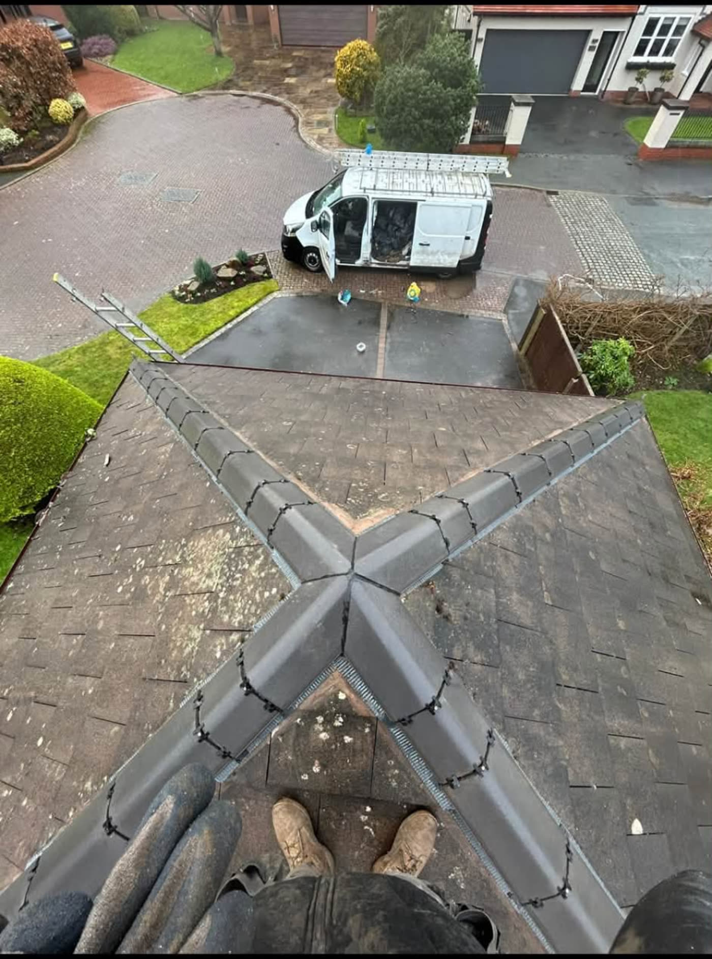 View from a completed pitched roof with new grey hip and ridge tiles, with the MB Roofline & Joinery work van on the drive below