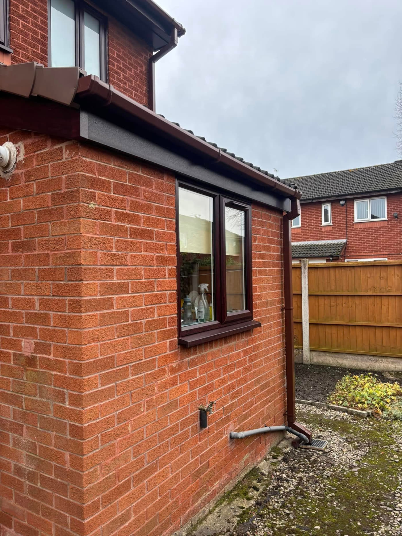 New brown uPVC fascias, soffits, guttering and downpipe fitted to a red brick house