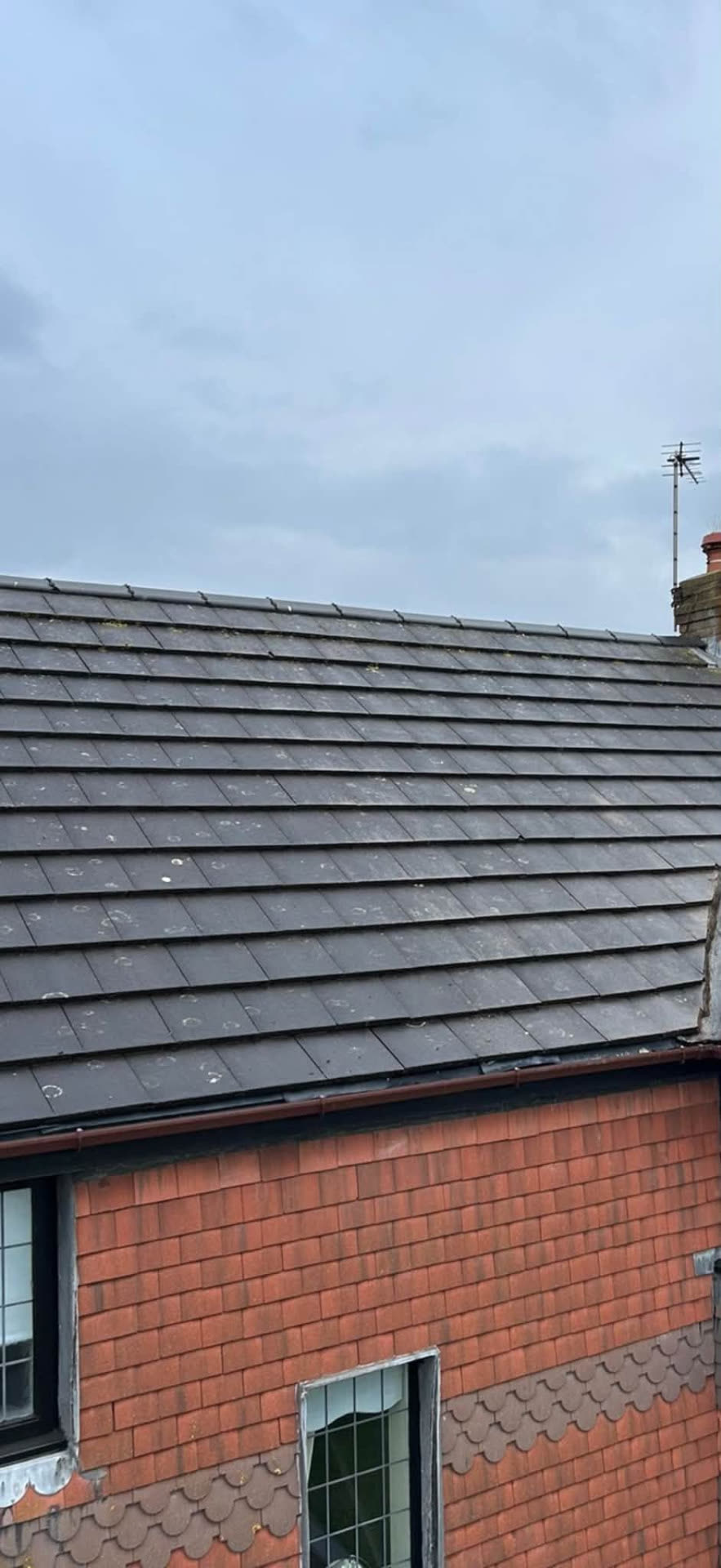 Slate-grey flat tiled roof finished with a new black fascia and guttering